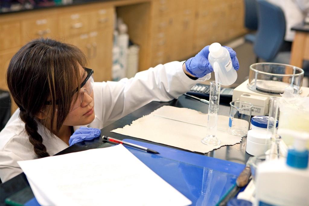 A female student fills test tubes in a research lab