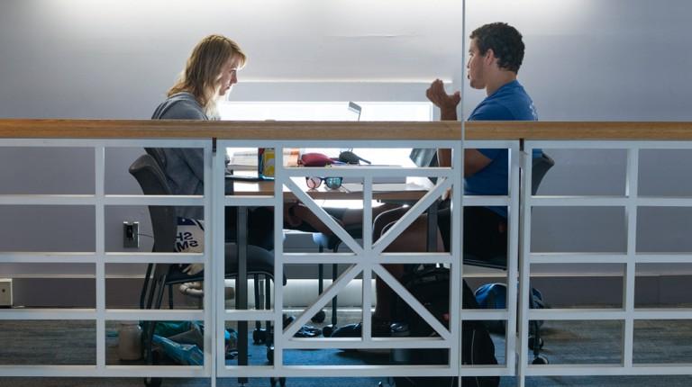 Two students talk while sitting in the Portland Campus library