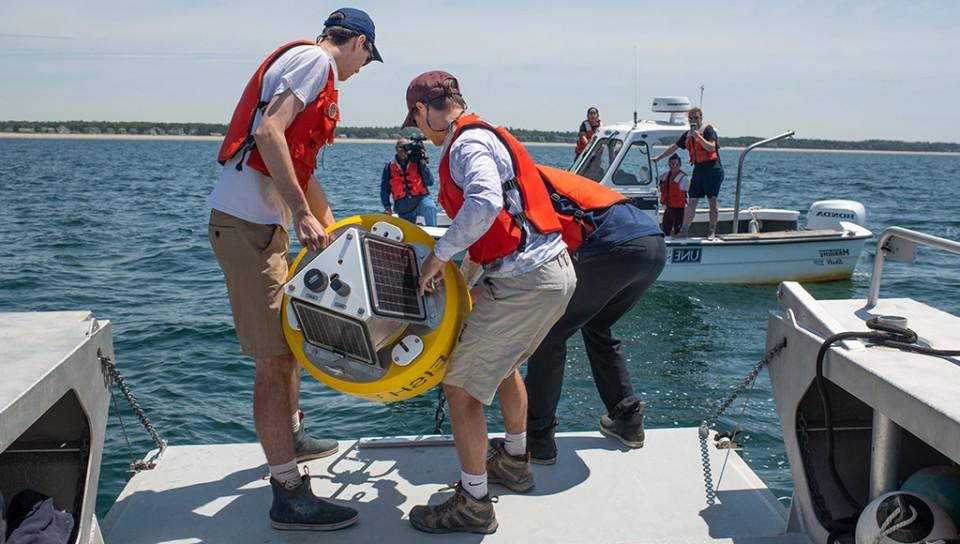 Students on a boat preparing a white shark buoy for deployment