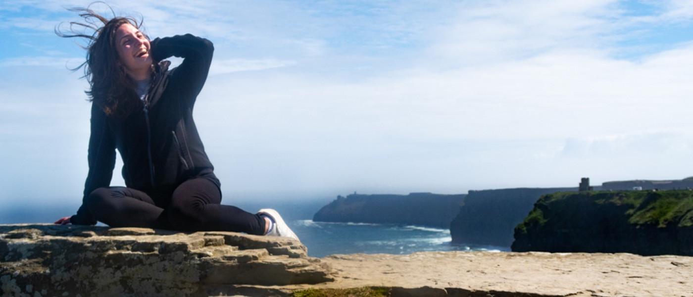 A student sits overlooking Ireland cliffs on the ocean