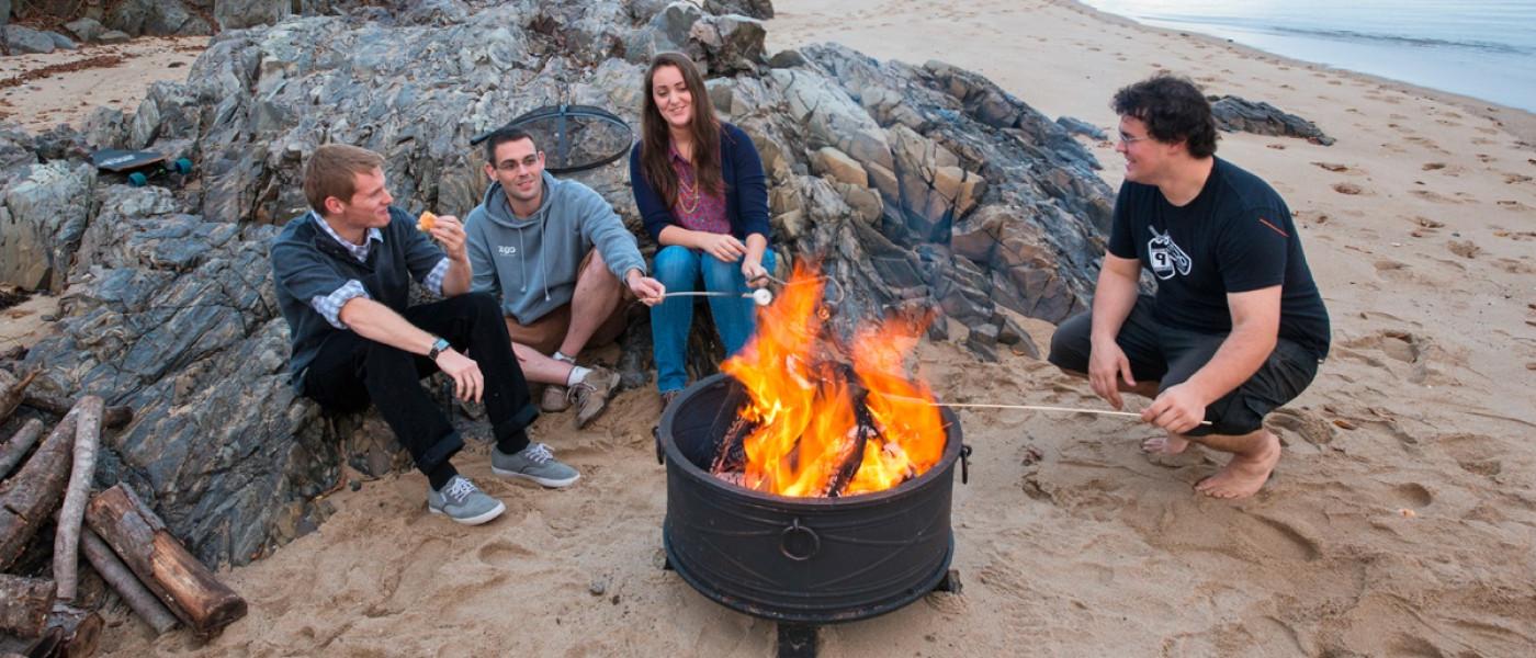 Four students having a bon fire on Freddy Beach