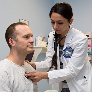 A U N E osteopathic medicine student listening to the heartbeat of a patient